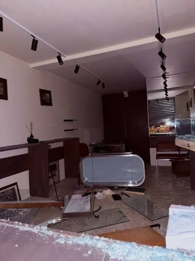 Intérieur d'une boutique dévastée, mobilier renversé et verre au sol